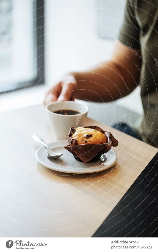 Anonymous person in cafe with muffin and coffee dessert sweet confection pastry confectionery coffee break treat serve food fresh tasty delicious yummy