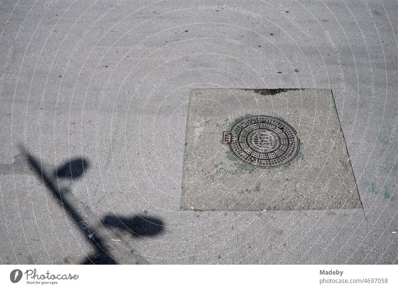 Round manhole cover in repaired gray asphalt in summer sunshine in the streets of Adapazari in Sakarya province in Turkey City cityscape Asia Minor adapazari