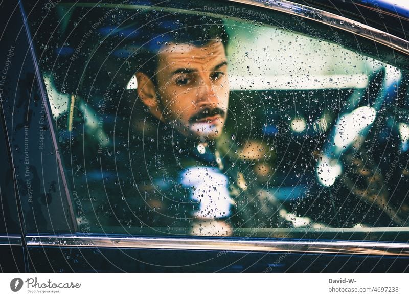 Man looks depressed from car in rainy weather Rainy weather Sit Car window raindrops Window pane Bad weather dejected depressive Exasperated Reflection