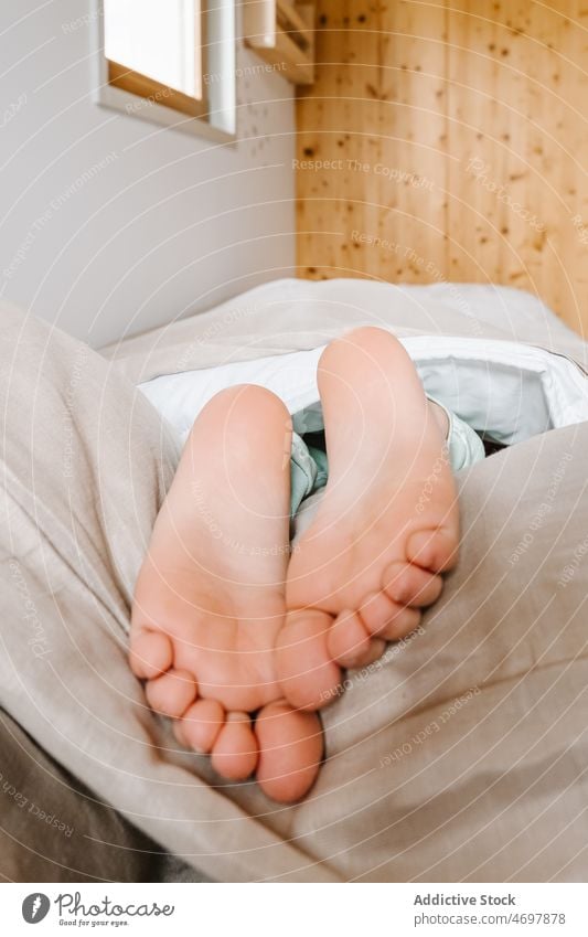 Unrecognizable child lying barefoot in bed little care healthy kid room comfort alone childhood human casual chilling beautiful sleep leg love toe fingers cute