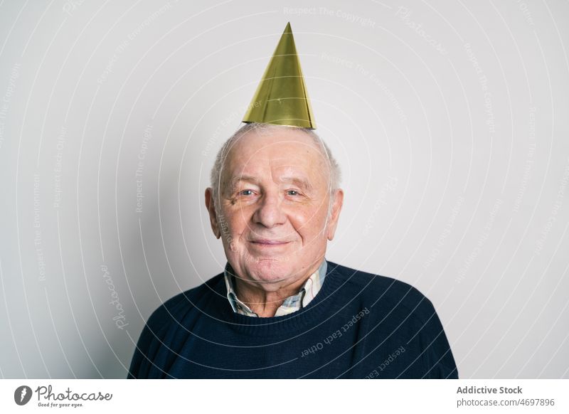 Cheerful elderly man in party hat in studio birthday laugh celebrate holiday senior fun joy happy male festive having fun humor cheerful delight excited