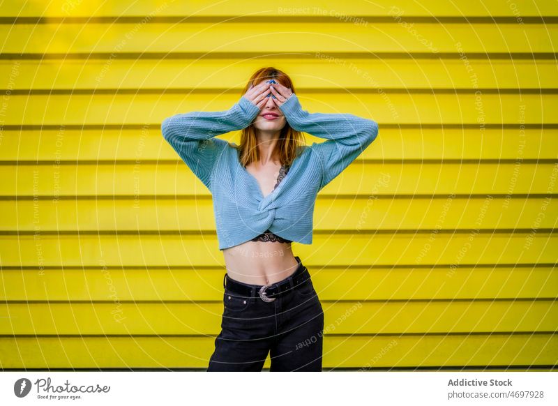 Unrecognizable woman covering eyes near wall cover eyes surprise style street trendy hide feminine fashion city female charming lady wear urban light anticipate