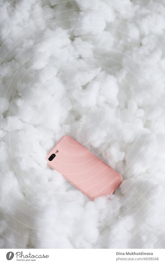 A mobile phone in a candy color pink case on fluffy texture. Cloud Technology concept. Mobile app. Social media. Devops Technology. Computer science and cloud solutions. IT industry.