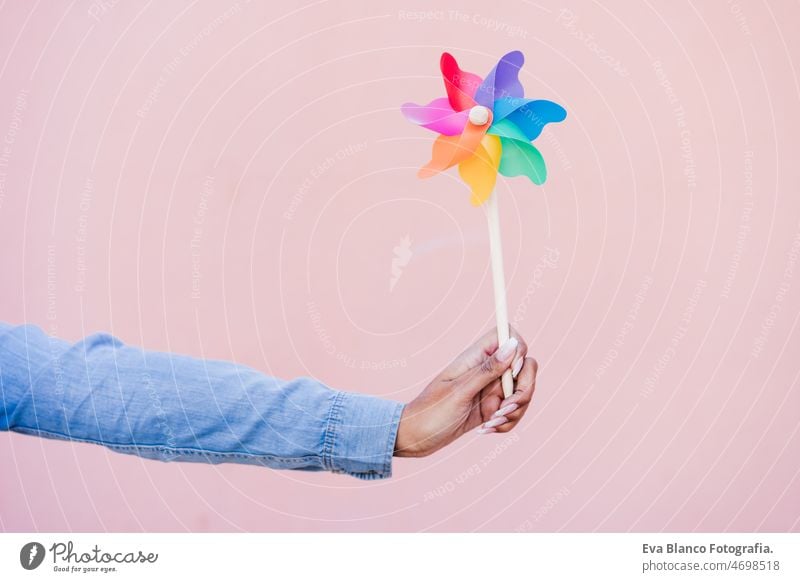 close up of woman holding colorful pinwheel. pink background,wind energy windmill hispanic afro sustainability reduce reused recycle city happy smiling spring
