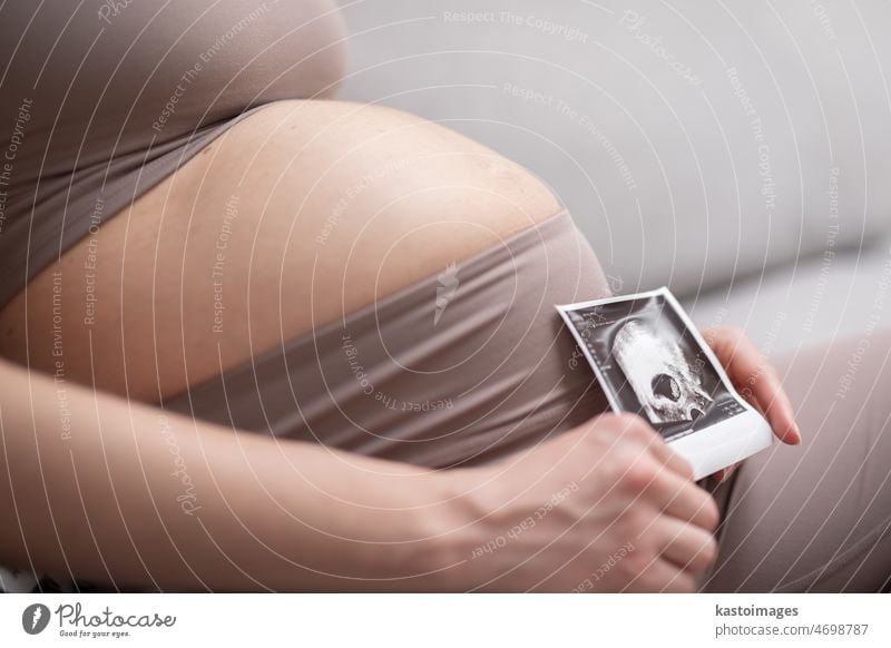 Pregnant woman belly. Pregnancy Concept. Pregnant tummy close up. Detail of pregnant woman holding ultrasound photo of her embryo child. love beautiful embrio