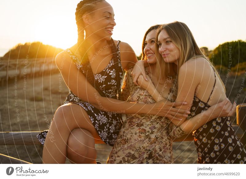 Optimistic multiracial girlfriends hugging on waterfront women leisure bonding rest recreation embrace tender cuddle relationship pastime fence diverse