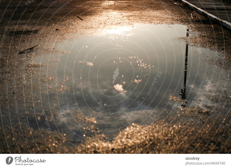 Puddle water reflection of sky clouds and power pole line puddle street rain wet old pavement road outdoor drop hole transportation weather city life rainy