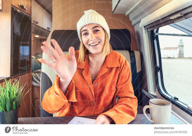 Happy woman waving on video call from her campervan happy looking camera videoconference remote work travel camper van smiling person chat interview talking