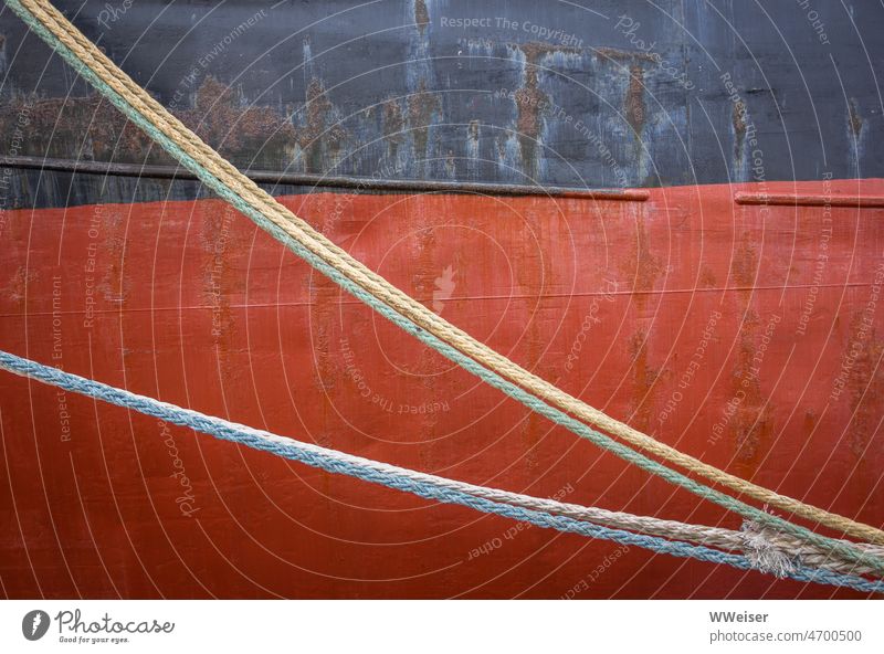 Ropes hang in front of the wall of a huge ship across the picture Diagonal Red Abstract Maritime Watercraft Dew Across Hang Rust colors colored Paintwork