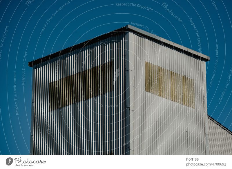 Corrugated metal facade of a warehouse Corrugated iron wall Warehouse Industrial plant Blue background Architecture High-rise Modern monotonously Blue sky Sky