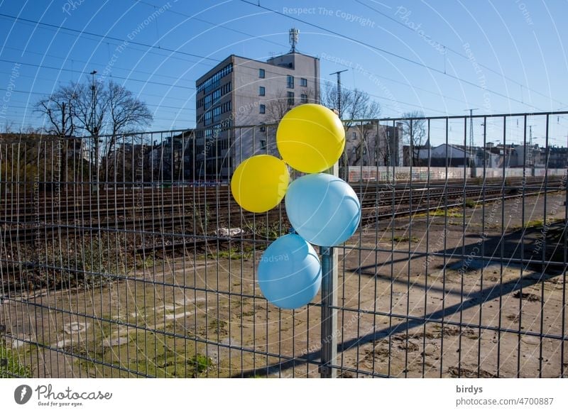Balloons in the colors of Ukraine on a fence along a dreary railroad line. national balloons Dove of peace Peace message War War of aggression Longing for peace