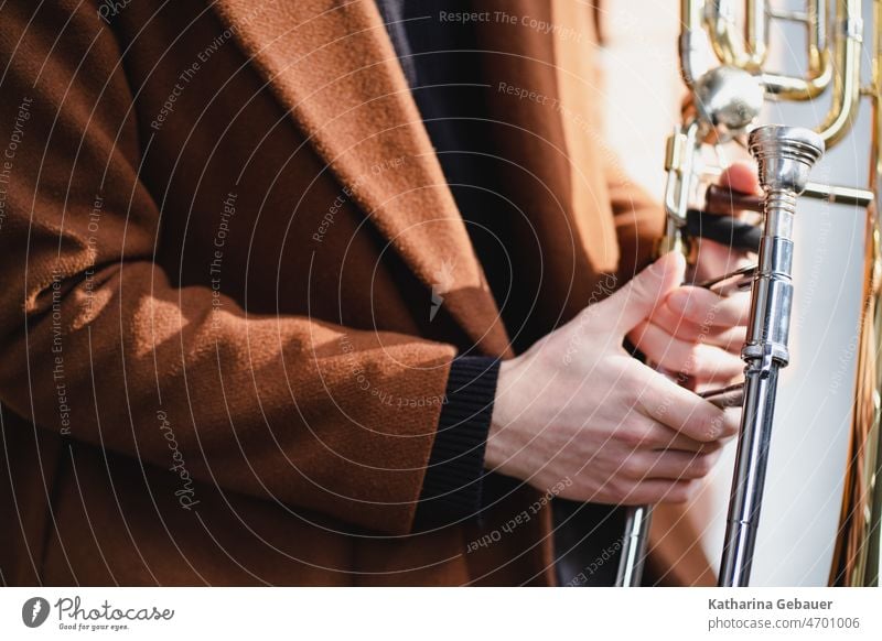 Ban with red coat holds trombone Trombone Trombonist Musician play music Brass instrument tool Musical instrument Winds Detail