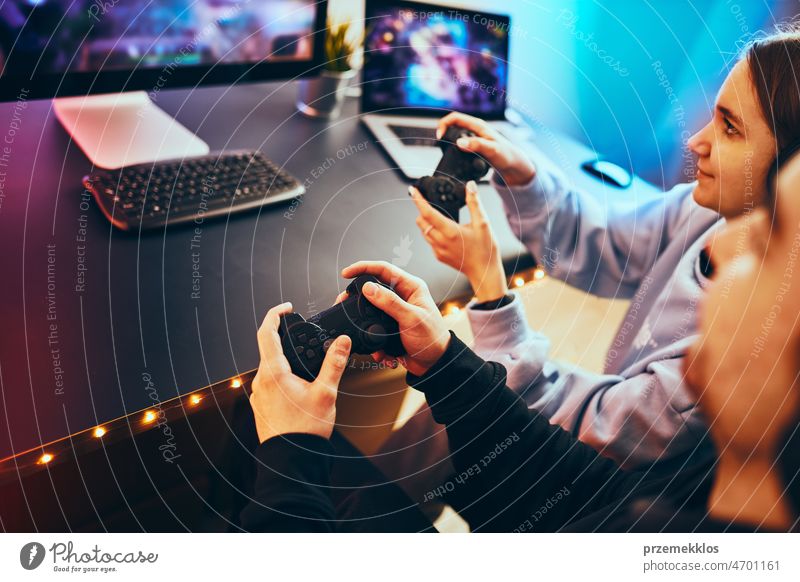 Friends playing video game at home. Gamers playing online in dark room lit  by neon lights. Competition and having fun - a Royalty Free Stock Photo  from Photocase