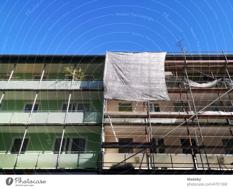 Scaffolding with tarpaulin on the facade two apartment buildings in summer against blue sky in Bielefeld in the Teutoburg Forest in East Westphalia-Lippe