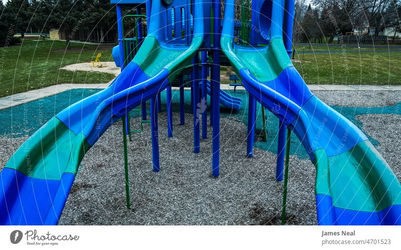 Pair of slides in autumn at local park in shades of blue playground pair plastic equipment fun grass green outdoors playing background old playful rural scene