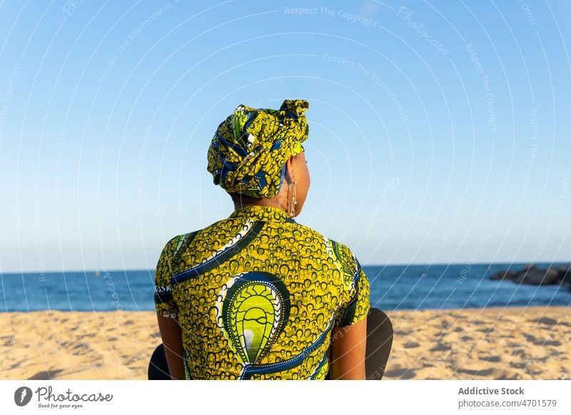 Black woman resting on beach sunlight summer sea blue sky weekend daytime calm female headscarf tradition sand shore relax african american black ethnic water