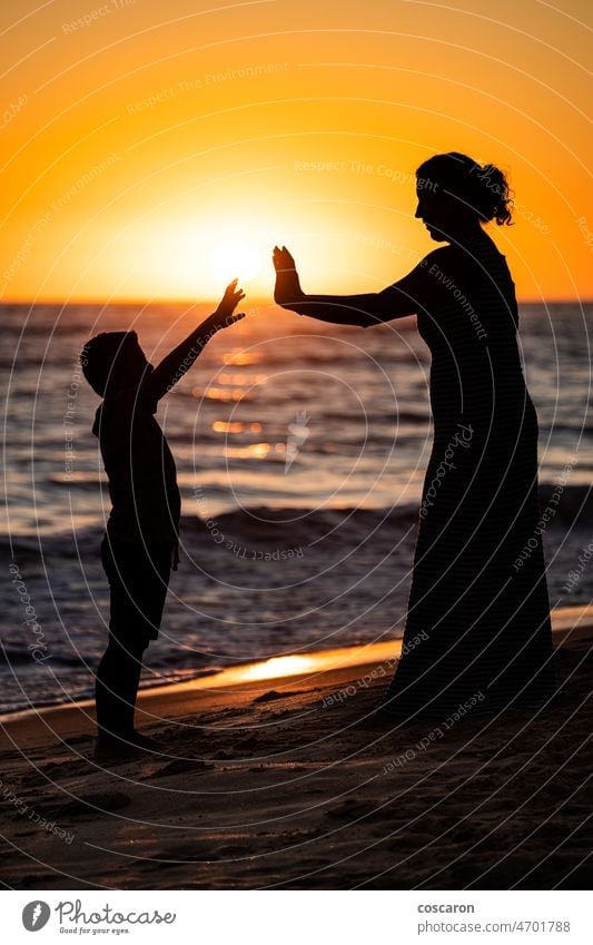 Mother and son holding hands on a beach at sunset baby cheerful child coast daughter enjoy enjoying family female fun girl happiness happy holiday holidays kid