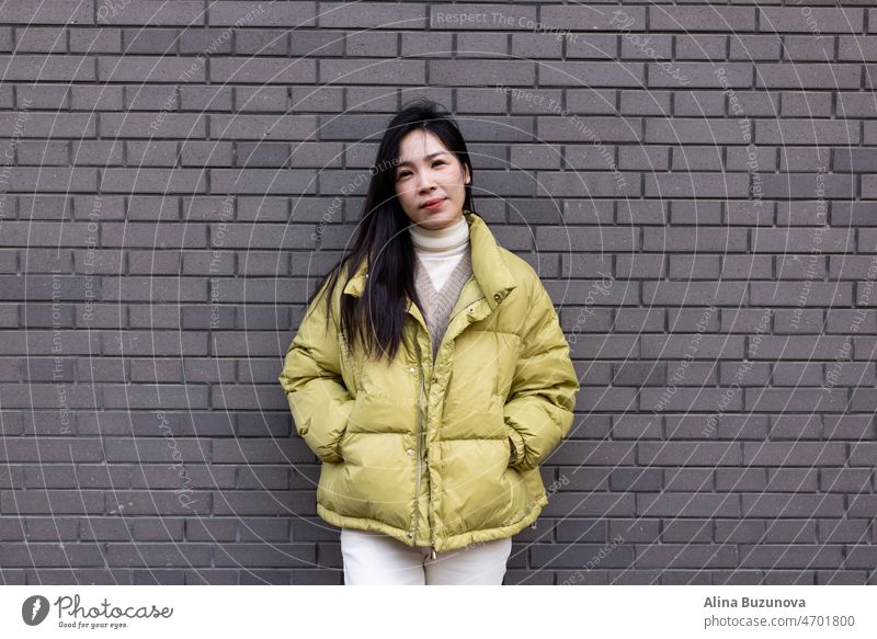 Candid lifestyle portrait of Stylish Young Asian beautiful woman standing outdoor near gray brick wall at spring or autumn season. business student person