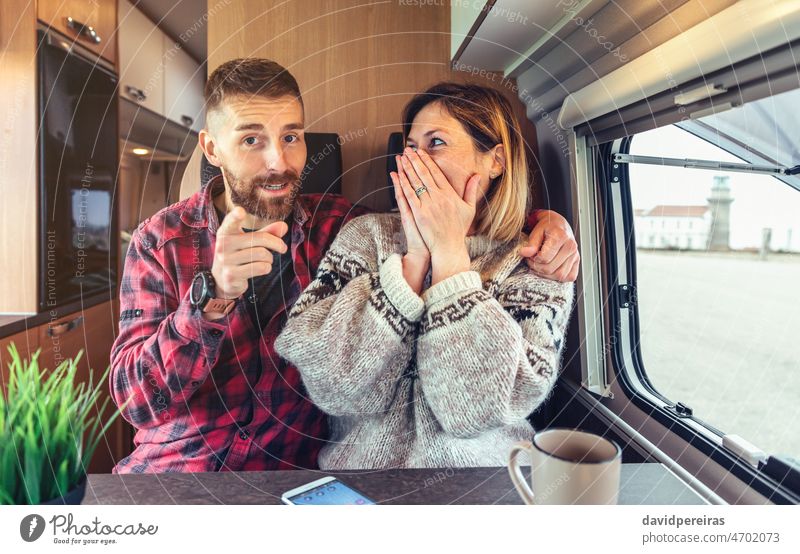 Happy couple talking and joking looking at camera on video call from their campervan happy looking camera smiling pointing travel excited emotional camper van