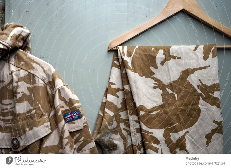 Old military jackets in brown and beige with camouflage pattern and Union Jack on the sleeve in front of an old factory in the Margaretenhütte district of Giessen on the river Lahn in the German state of Hesse