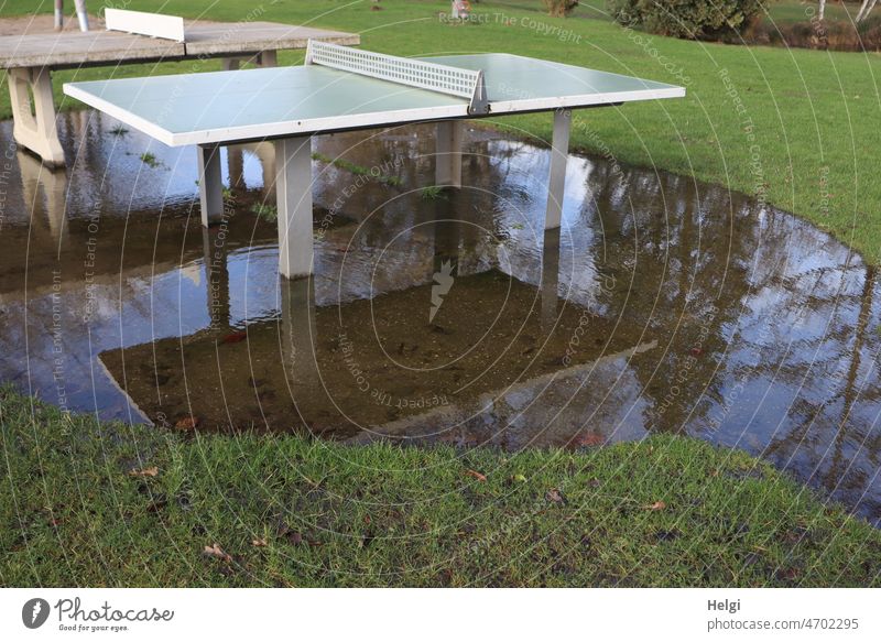 wet - two ping pong tables standing on a meadow in a big rain puddle with reflection Table tennis table Sports Puddle Rain puddle Water Meadow trees Wet