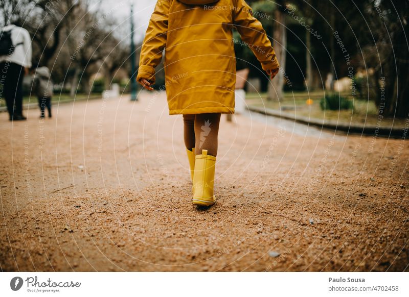 Rear view girl with yellow rubber boots walking Yellow Rubber boots Jacket Girl Child Infancy Human being Exterior shot Colour photo Playing Day Joy Wet 1 Rain