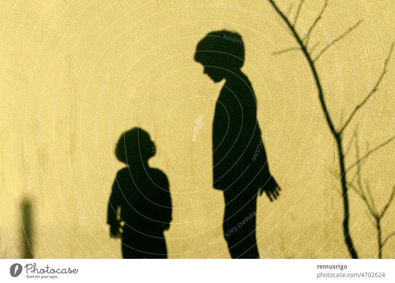 Shadows of children playing on the wall. Looking up at brother. background black boy childhood kids family friends scene shadow silhouette together two