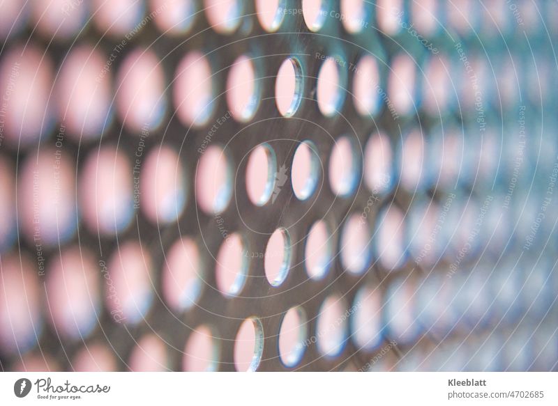 Stainless steel perforated sheet with light pink tones in background - partial blur High-grade steel Plate with holes Pink Background picture Partial blurring