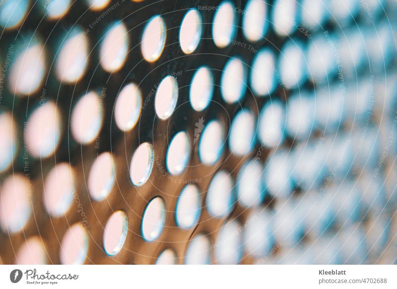Stainless steel perforated sheet with light bluish background - partial blur High-grade steel Plate with holes Artistic bluish coloring blurriness hazy