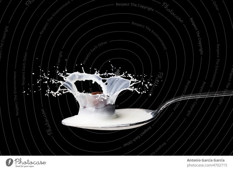 Spoon full of milk splashing on black background high speed splashed aquatic glasses drink liquid drop white isolated beverage abstract blue cocktail food fresh