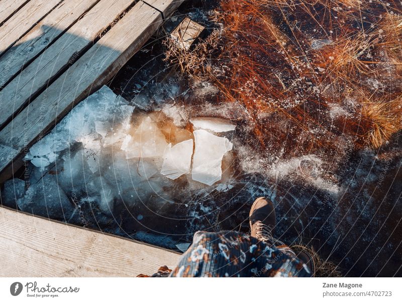 A woman sitting by the frozen river, early spring, melting ice outdoors wood ice melting sunlight contrast daylight enjoying outdoors walk walk in nature chill