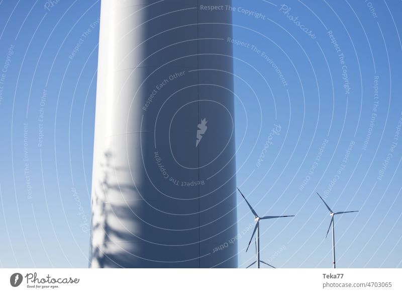 a wind turbine park in front of a blue sky wind turbines wind power wind energy modern wind turbine green energy cloudy party cloudy white shadow volt amper