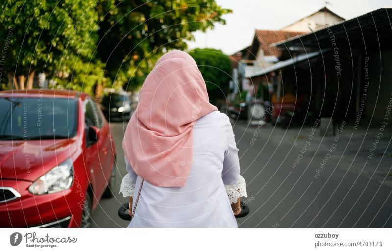 Rear view young asian muslim woman cycling in the street. Young woman with headscarf biking. sport islam bicycle travel action exercise joy mobility progress