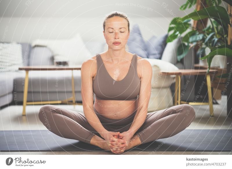 Young beautiful pregnant woman practising yoga at home in her living room. Motherhood, pregnancy, healthy lifestyle, well being and yoga concept. mother baby