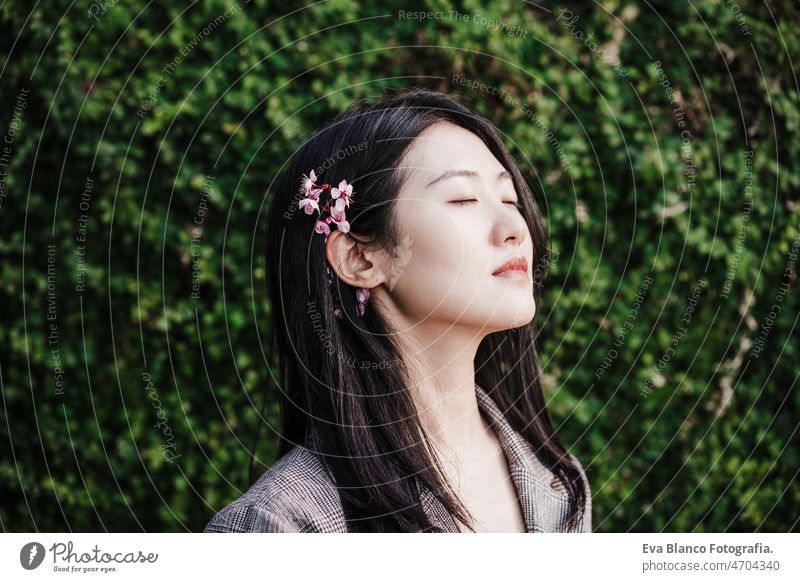 portrait of beautiful chinese asian woman with eyes closed and almond tree flowers.Spring time,relax spring nature city oriental young green adult blossom day