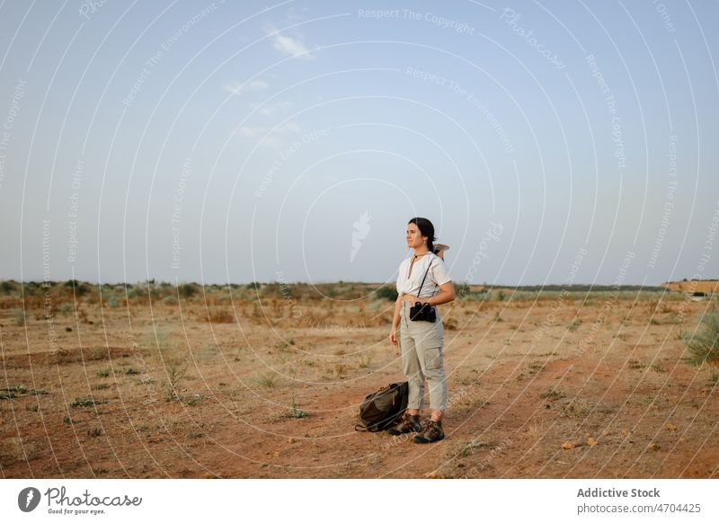 Woman with binoculars in desert field woman traveler trip adventure arid journey explore admire enjoy barren dry thoughtful harmony pensive waterless tourism