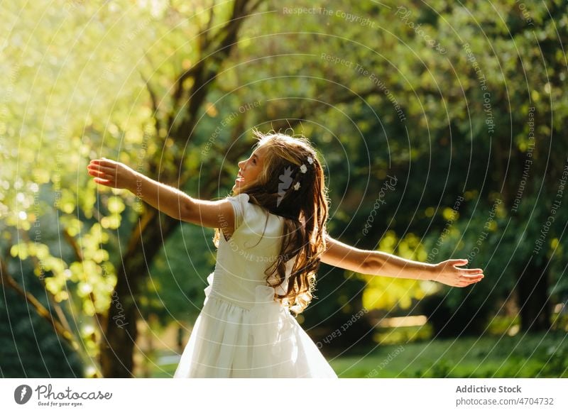 Happy girl dancing in park in First Communion dress catholic first communion religion holy communion summer nature female cheerful happy carefree joy smile