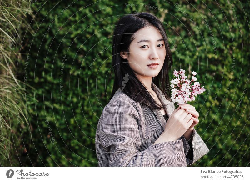 beautiful chinese asian woman holding almond tree flowers.Spring. selective focus on flowers portrait spring nature city oriental young green adult blossom day