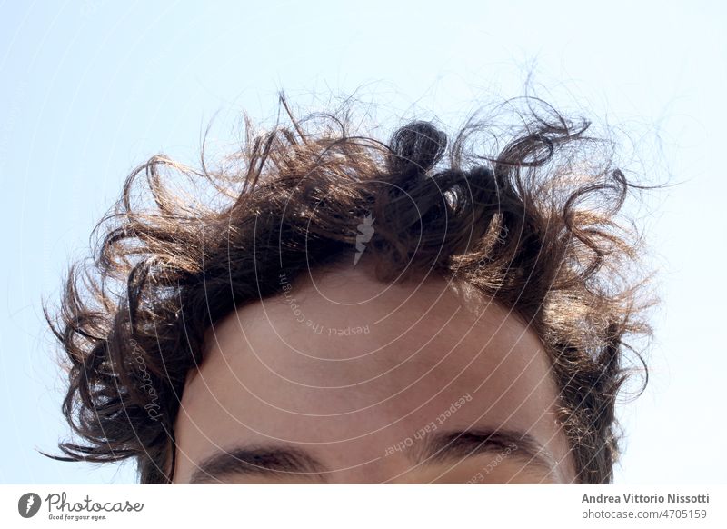 Close up on a male teenager forehead face closeup eyes closed eyes outdoor sunny hair curly horizontal color image boy relax dreaming portrait sky imaging