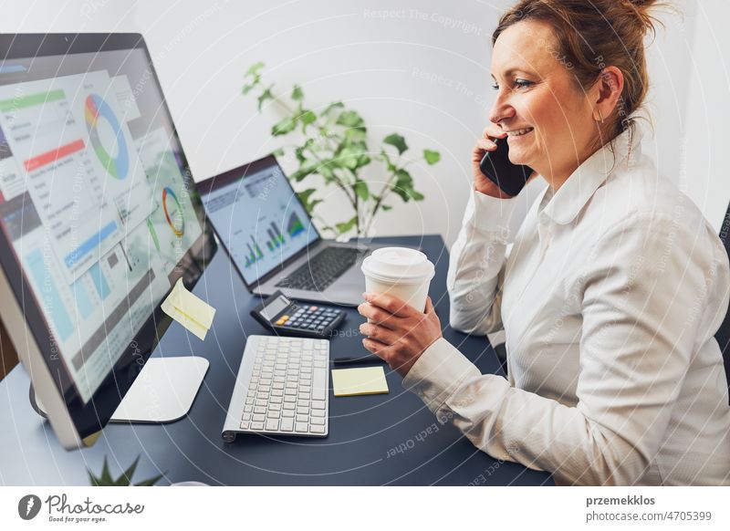Woman entrepreneur having business conversation on mobile phone. Businesswoman working with data looking at charts and graphs on screen call calling office