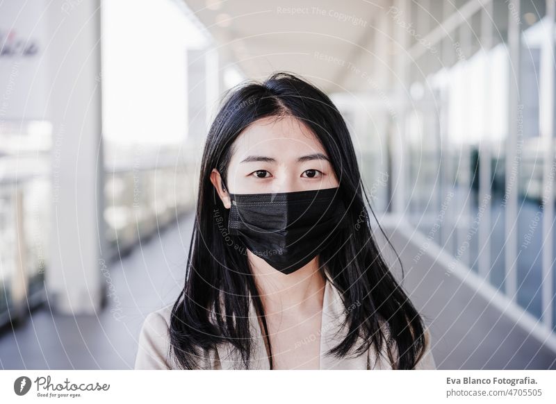 close up of young business woman wearing face mask in city. corona virus concept chinese pandemic office co working glass reflection asian entrepreneur