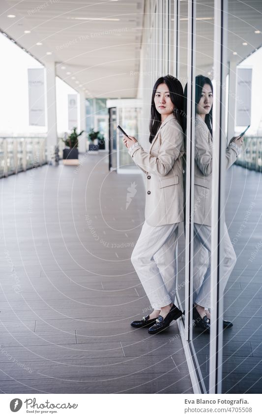 portrait of beautiful chinese business woman using mobile phone in building office. Technology asian laptop technology cafe coffee cafeteria tablet cheerful