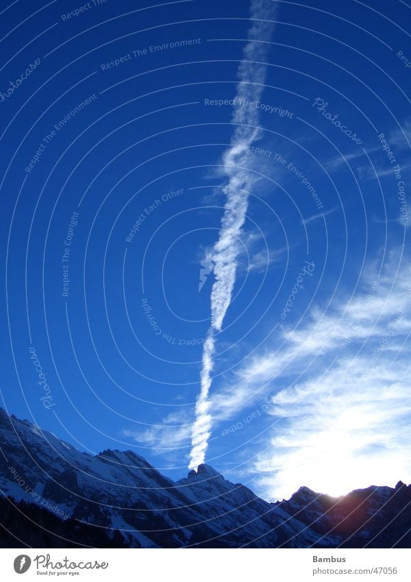 Early evening atmosphere in the Swiss Alps Vapor trail Clouds Mountain Sun Evening Snow Sky Blue