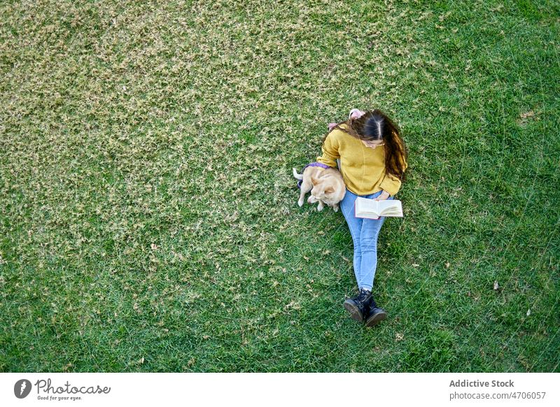 Faceless woman reading book on lawn near dog owner park animal pet pastime literature hobby bookworm story leisure canine friend female obedient loyal breed