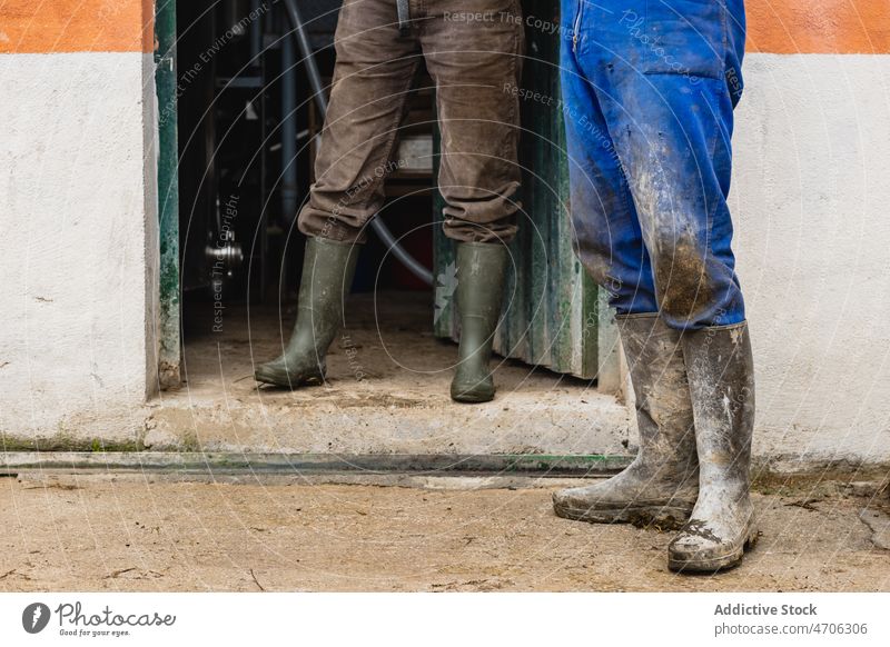 Unrecognizable farmers standing near building couple worker street countryside rural dirty industrial labor job workwear boot lifestyle profession mud messy