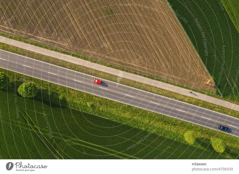 Aerial view of two lane road through countryside and cultivated fields with cars. Drone shot drone freeway trip aerial view agricultural automobiles copy space