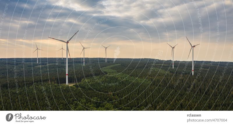 wind farm in the forest at sunset - energy production with clean and renewable energy - aerial shot turbine power environment fuel alternative drone electricity
