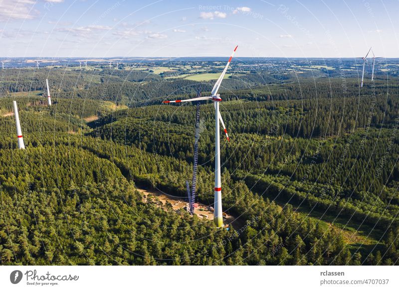 Aerial view of wind turbines or a wind farm under construction forest trees industry drone generator construction side aerial cloud renewable energy rotor blade