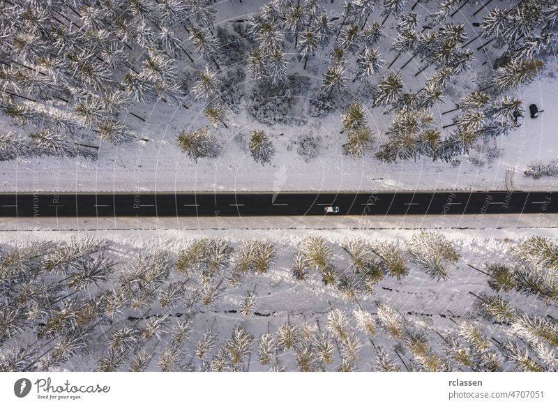 Winter snow covered pine forests and road with car bird's eye view winter drone aerial sunset snowy sunlight above flight day adventure background beautiful