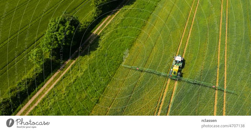 Aerial view of a tractor spraying the field. Chemistry in agriculture from drone view. Modern farming background concept. aerial above agricultural